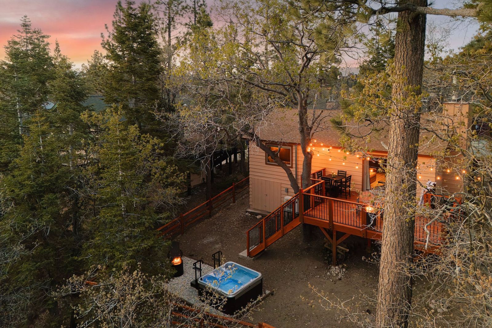 Aerial view of Chalet Étoile at dusk with string lights, deck, and hot tub