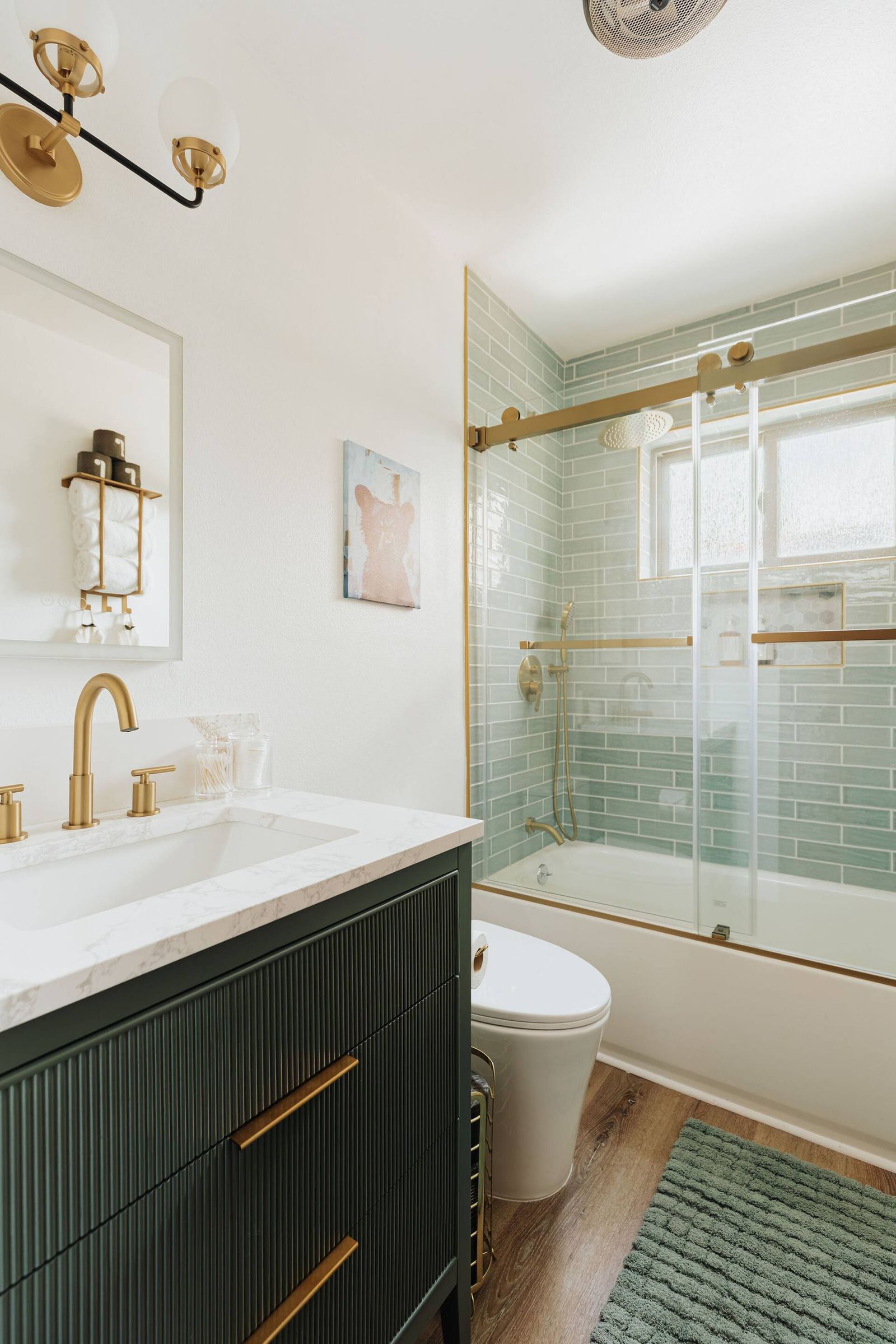 Bathroom vanity with green cabinet and touch-lit mirror