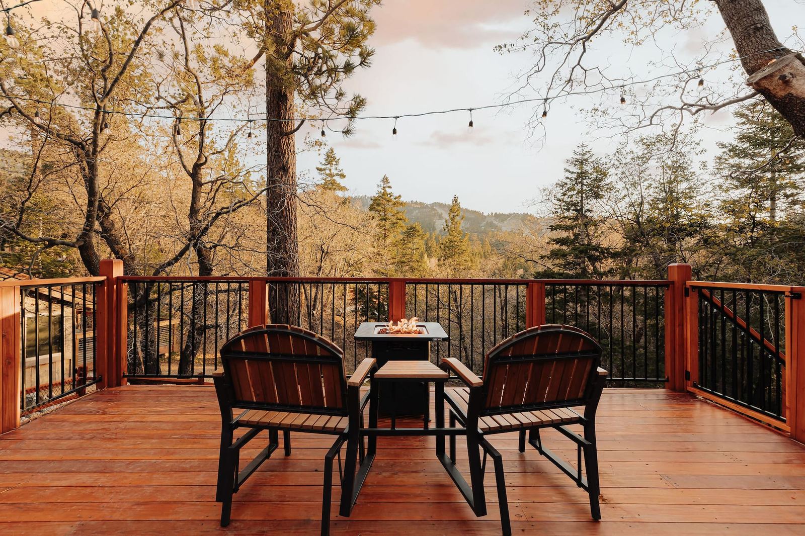 The string lit deck with the dining table, looking out over the trees