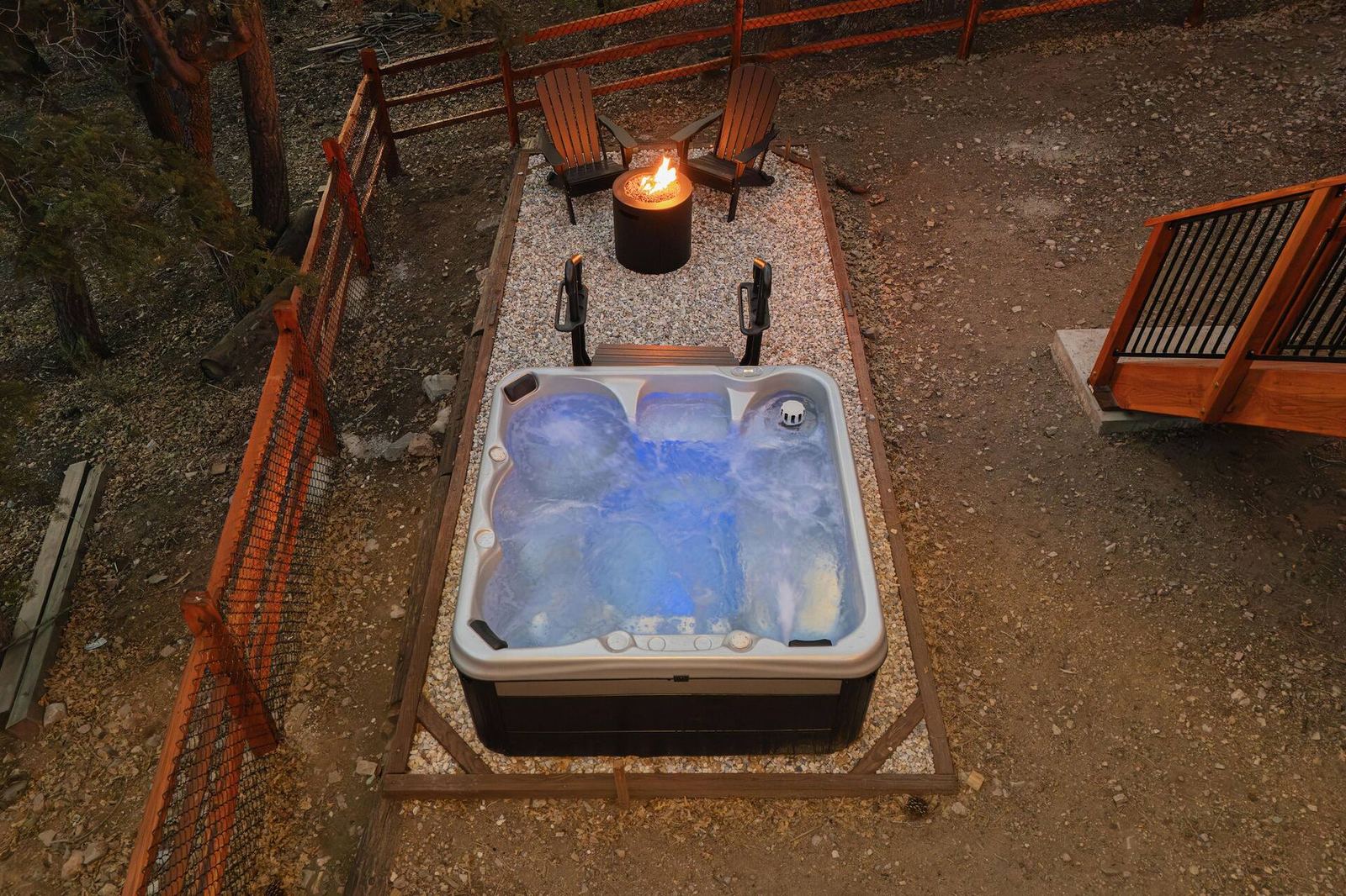 The hot tub and fire pit in the fenced backyard at Chalet Étoile